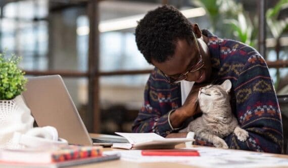cat snuggling with man in office