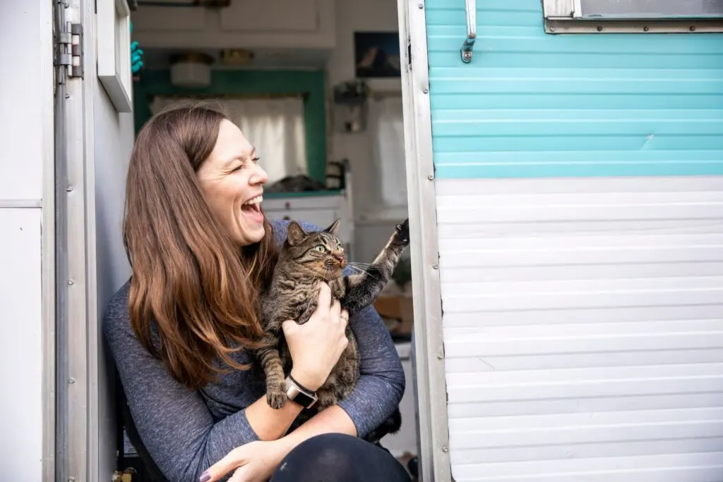 woman holds cat while camping in an rv with a cat